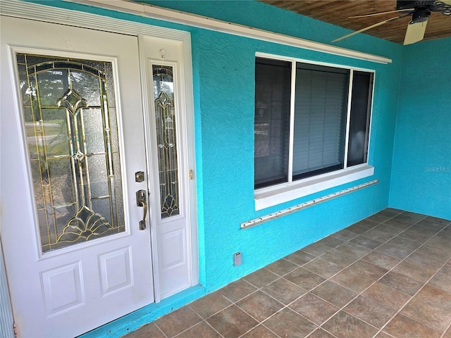 doorway to property featuring a ceiling fan and stucco siding