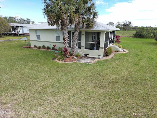 view of front facade featuring a front yard, a sunroom, and stucco siding