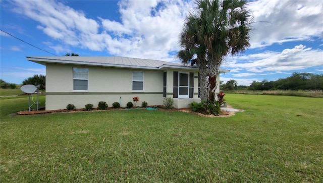 single story home with metal roof, a front lawn, and stucco siding