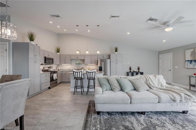 living area with high vaulted ceiling, visible vents, and ceiling fan with notable chandelier