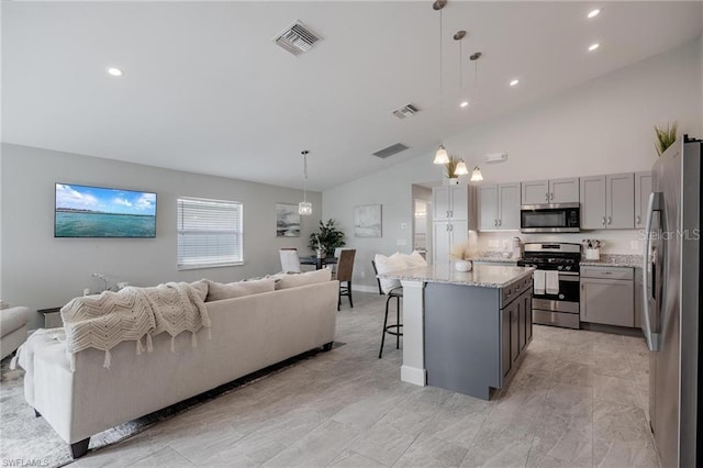 kitchen featuring light stone counters, visible vents, open floor plan, appliances with stainless steel finishes, and gray cabinets