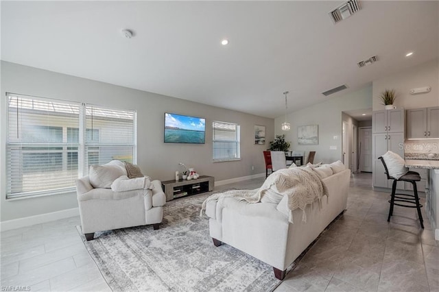 living area featuring lofted ceiling, visible vents, and baseboards