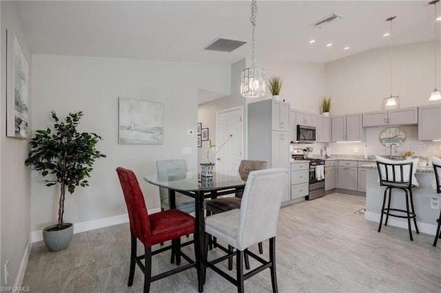 dining room featuring high vaulted ceiling, visible vents, and baseboards