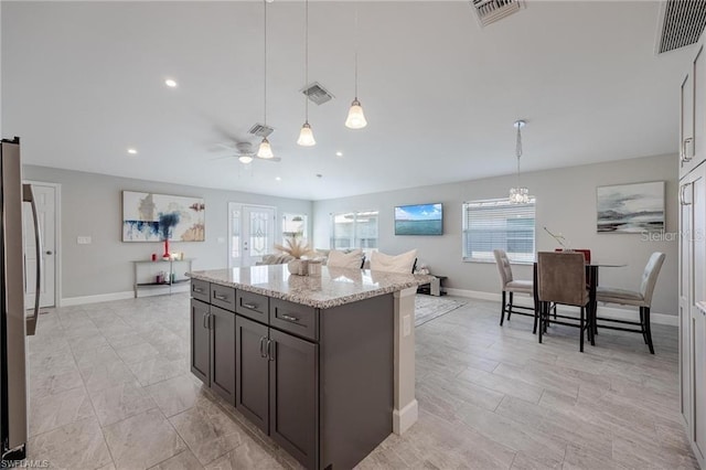 kitchen featuring light stone counters, visible vents, and decorative light fixtures