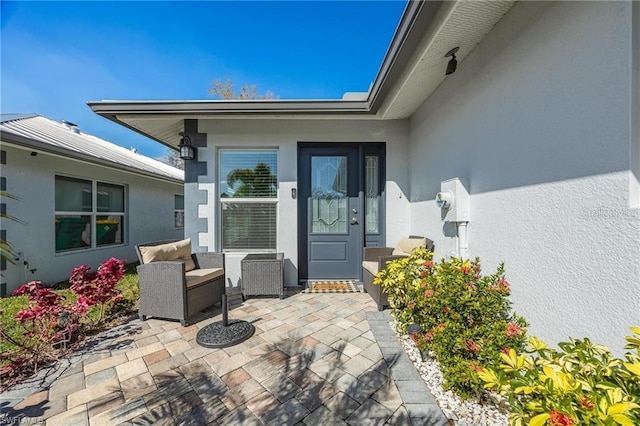 entrance to property featuring a patio area and stucco siding