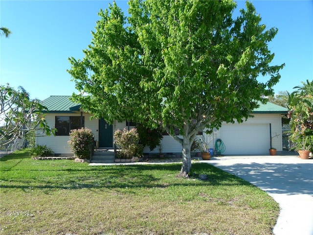 obstructed view of property featuring a garage, driveway, metal roof, and a front yard