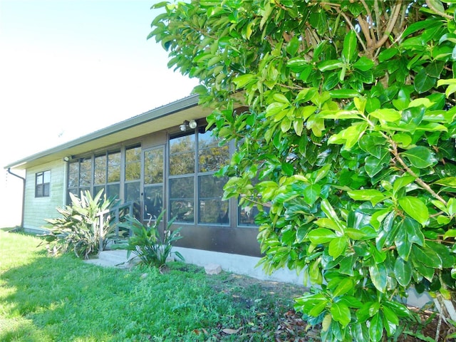 view of property exterior with a sunroom and a yard