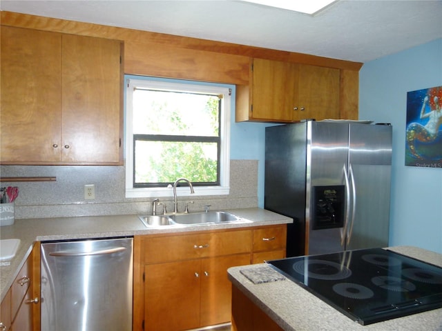 kitchen with brown cabinets, stainless steel appliances, a sink, and light countertops