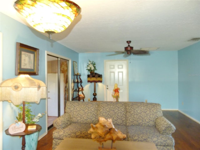 living room with a ceiling fan, baseboards, visible vents, and wood finished floors