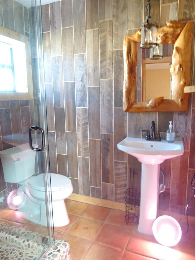 bathroom featuring toilet, a sink, tile walls, a shower stall, and tile patterned floors