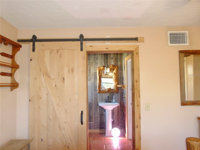 interior space featuring a barn door, a sink, and visible vents