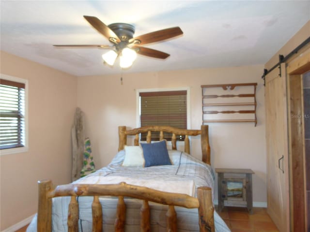 bedroom with a barn door, baseboards, a ceiling fan, and light tile patterned flooring