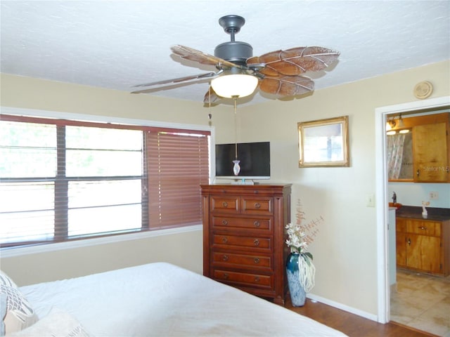 bedroom with ceiling fan, a textured ceiling, baseboards, and wood finished floors