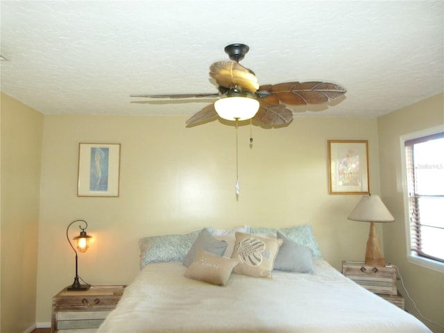 bedroom with a ceiling fan, multiple windows, and a textured ceiling