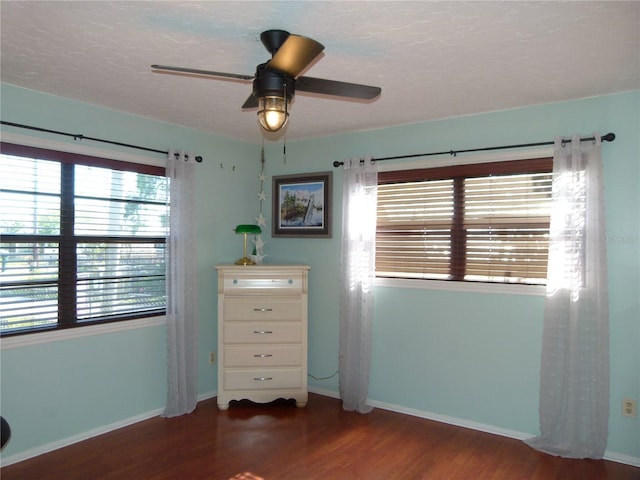 unfurnished bedroom with a ceiling fan, a textured ceiling, baseboards, and wood finished floors