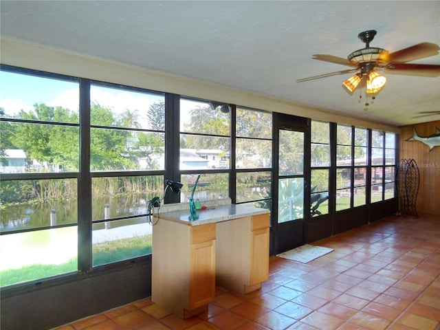 unfurnished sunroom featuring a water view and ceiling fan