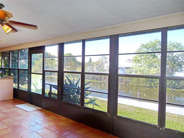 unfurnished sunroom featuring a water view and ceiling fan