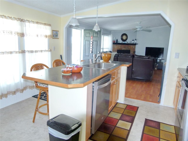 kitchen featuring dishwasher, dark countertops, a kitchen breakfast bar, crown molding, and a sink