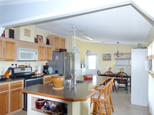 kitchen featuring appliances with stainless steel finishes, dark countertops, a breakfast bar, and a kitchen island with sink