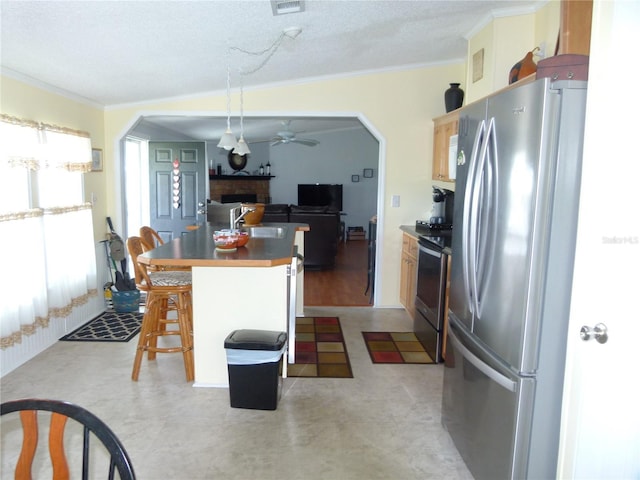 kitchen with arched walkways, appliances with stainless steel finishes, crown molding, a fireplace, and a sink