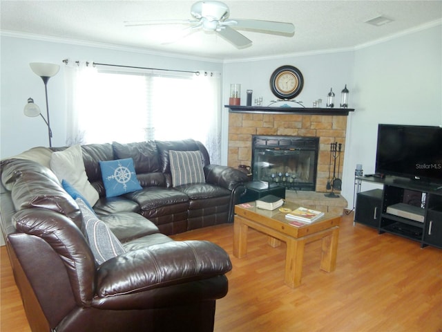 living room featuring a stone fireplace, wood finished floors, visible vents, and crown molding