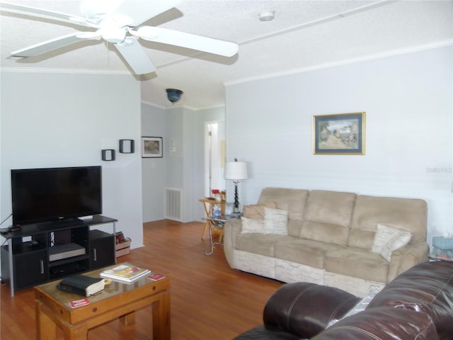 living room with a ceiling fan, visible vents, wood finished floors, and ornamental molding