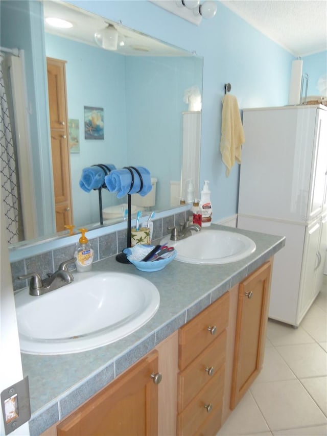 bathroom with a textured ceiling, double vanity, a sink, and tile patterned floors