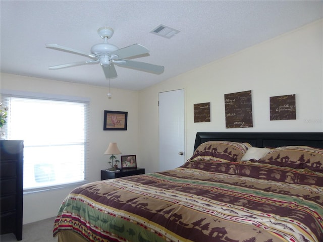 bedroom featuring carpet, lofted ceiling, visible vents, a ceiling fan, and a textured ceiling