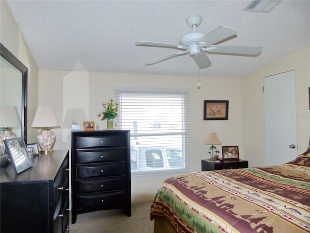 bedroom with a textured ceiling, carpet, visible vents, and a ceiling fan