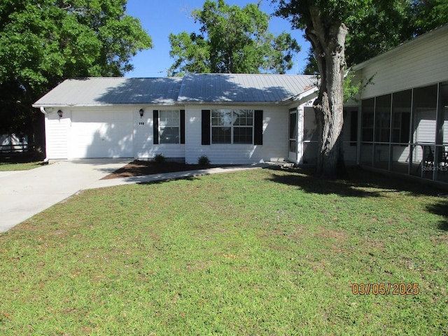 ranch-style home featuring a garage, driveway, metal roof, and a front yard