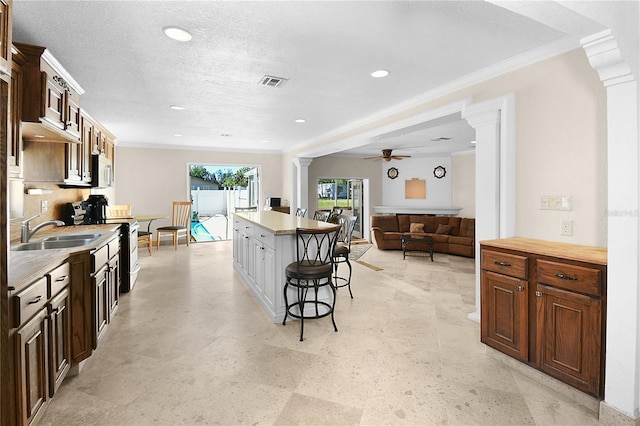 kitchen with visible vents, a breakfast bar, electric range oven, decorative columns, and a sink