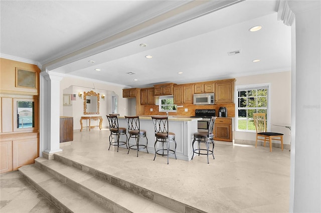 kitchen with visible vents, ornamental molding, a kitchen bar, stainless steel microwave, and backsplash