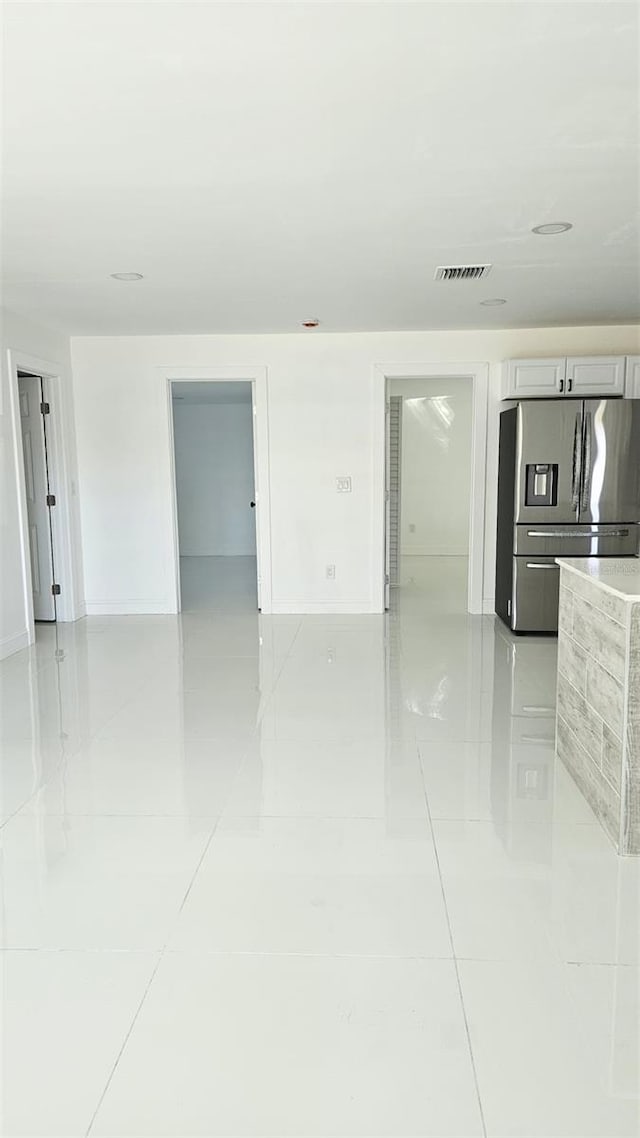 empty room with baseboards, visible vents, and light tile patterned floors