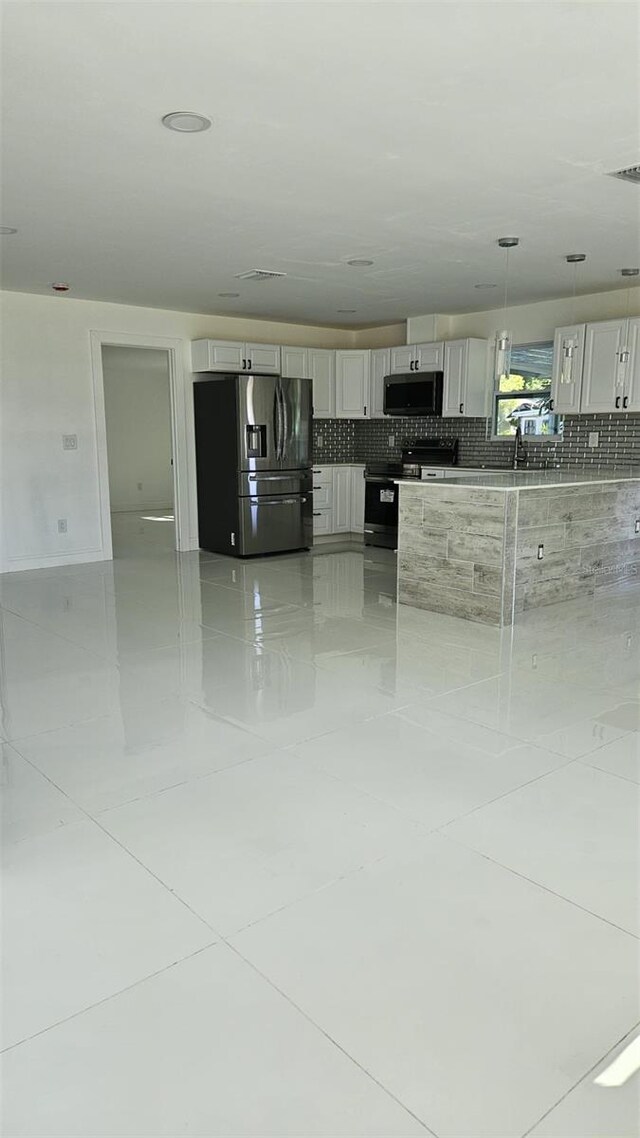 kitchen featuring stainless steel fridge, electric stove, visible vents, decorative light fixtures, and decorative backsplash