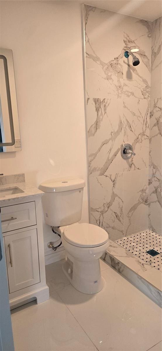 bathroom featuring marble finish floor, toilet, vanity, and a marble finish shower