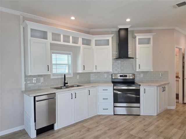 649 SW 34th Cv Unit 392, Okeechobee, FL 34974 - kitchen featuring appliances with stainless steel finishes, wall chimney exhaust hood, light wood-type flooring, white cabinetry, and crown molding