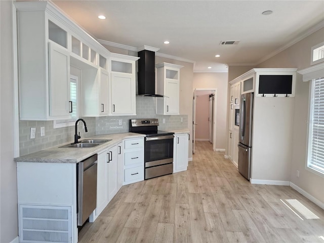 649 SW 34th Cv Unit 392, Okeechobee, FL 34974 - kitchen featuring appliances with stainless steel finishes, wall chimney exhaust hood, tasteful backsplash, white cabinetry, and light wood finished floors