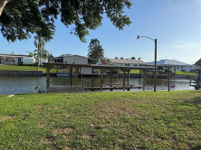 dock area with a yard, boat lift, a residential view, and a water view