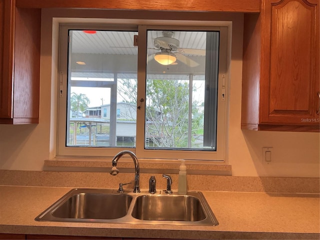 kitchen with a sink, light countertops, a ceiling fan, and a healthy amount of sunlight