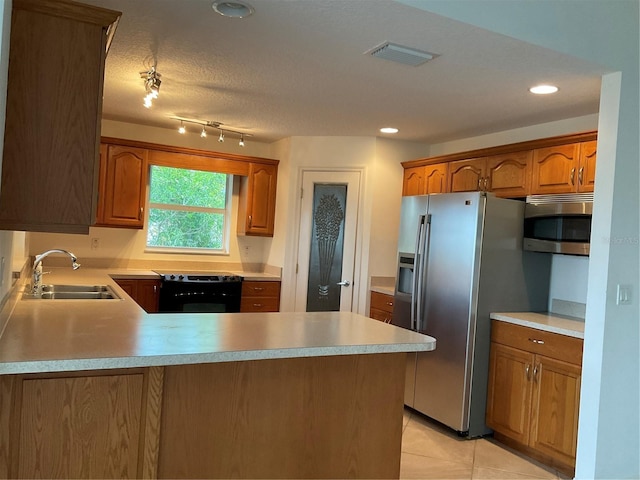 kitchen featuring visible vents, a peninsula, light countertops, a sink, and appliances with stainless steel finishes