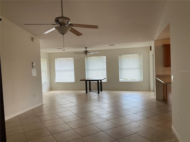 unfurnished room featuring a ceiling fan, baseboards, and light tile patterned flooring