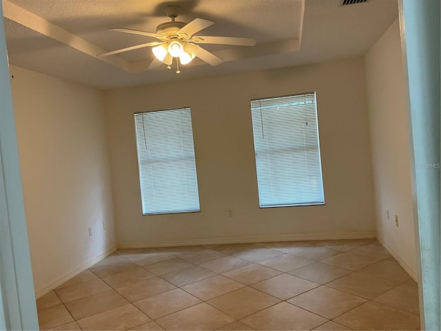 spare room featuring light tile patterned floors, a raised ceiling, and a ceiling fan