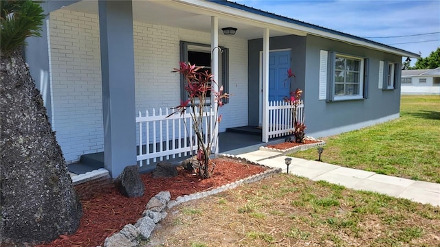 3007 SE 34th Ct, Okeechobee, FL 34974 - view of exterior entry with brick siding, a lawn, and a porch