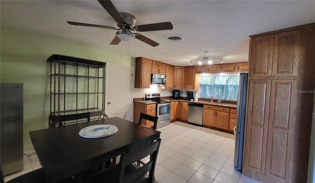 3007 SE 34th Ct, Okeechobee, FL 34974 - kitchen with light tile patterned floors, brown cabinets, a sink, stainless steel appliances, and ceiling fan