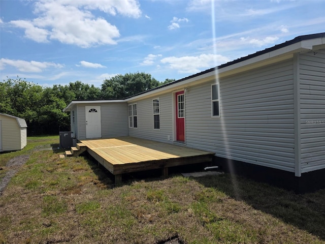 7895 NW 84th Ct, Okeechobee, FL 34972 - rear view of property featuring a lawn, a wooden deck, central AC, an outdoor structure, and a shed