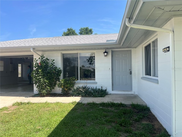 entrance to property featuring roof with shingles and concrete block siding
