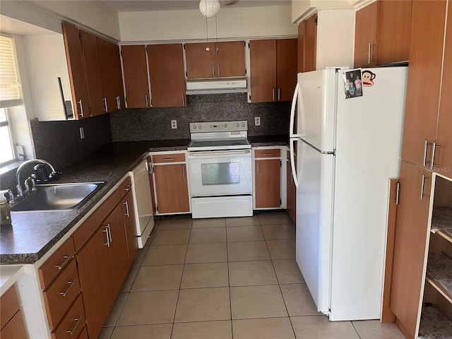 kitchen featuring white appliances, a sink, under cabinet range hood, dark countertops, and decorative backsplash