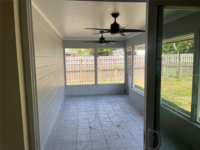 unfurnished sunroom featuring ceiling fan and plenty of natural light