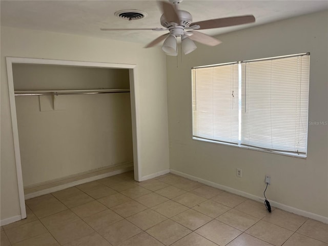 unfurnished bedroom featuring a closet, light tile patterned floors, a ceiling fan, and baseboards