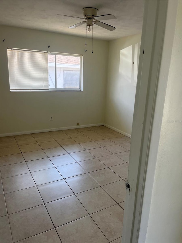 empty room with light tile patterned floors, ceiling fan, and baseboards